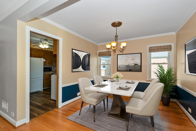 dining space featuring light wood-type flooring, baseboards, and ornamental molding