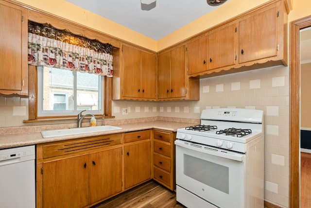 kitchen with a sink, light countertops, light wood-type flooring, white appliances, and backsplash