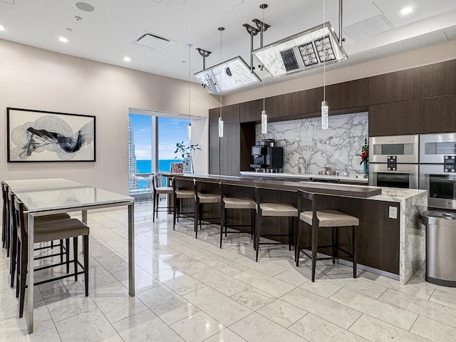 363 E Wacker Dr Unit 6306, Chicago, IL 60601 - kitchen with a kitchen bar, a large island, pendant lighting, dark brown cabinets, and backsplash