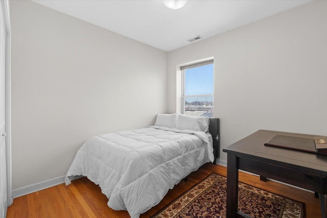 bedroom featuring wood finished floors, visible vents, and baseboards