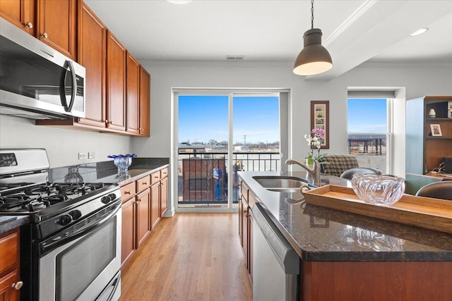 kitchen featuring visible vents, crown molding, brown cabinets, stainless steel appliances, and a sink