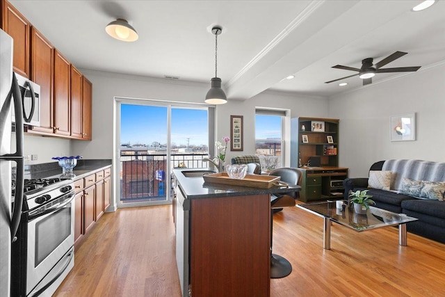 kitchen with a breakfast bar, a sink, light wood-style floors, appliances with stainless steel finishes, and open floor plan