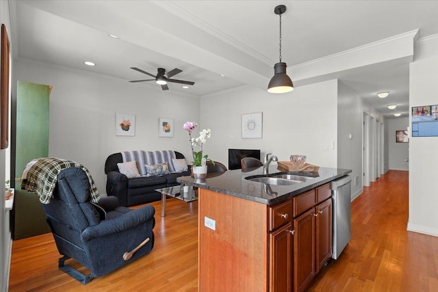 kitchen with light wood-type flooring, a sink, stainless steel dishwasher, open floor plan, and hanging light fixtures
