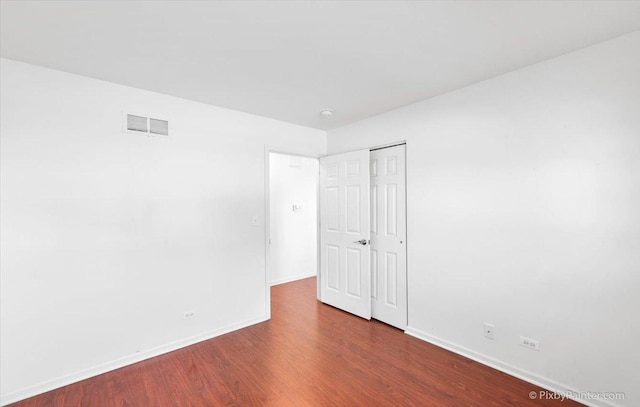 unfurnished room featuring wood finished floors, baseboards, and visible vents