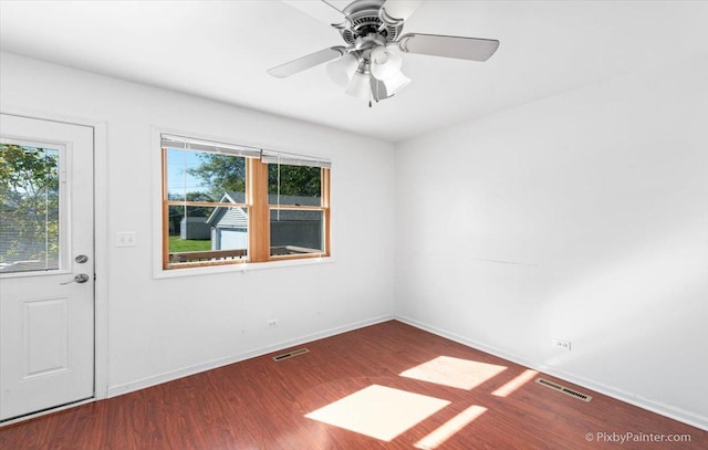 empty room with baseboards, ceiling fan, visible vents, and wood finished floors