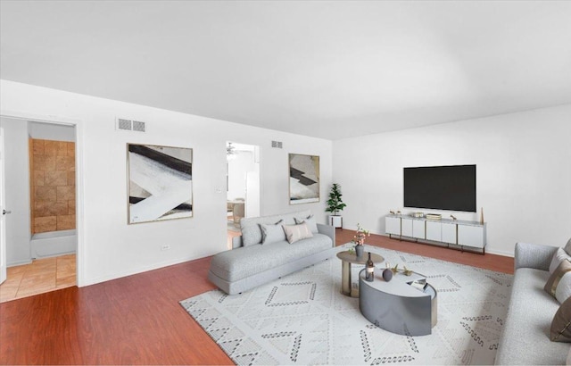 living room with baseboards, visible vents, and wood finished floors