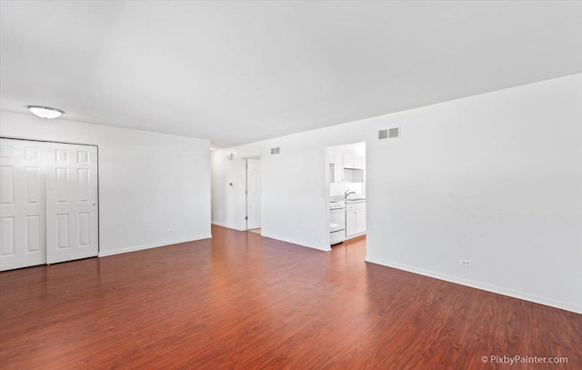 unfurnished living room with baseboards, dark wood-style flooring, and visible vents