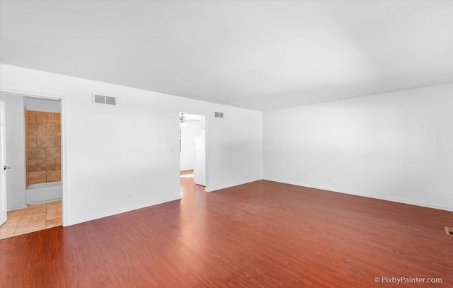 unfurnished room with baseboards, visible vents, and wood finished floors