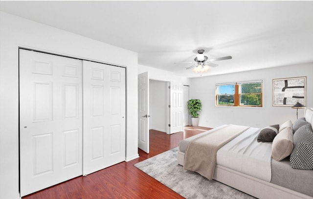 bedroom with baseboards, a closet, dark wood-type flooring, and a ceiling fan