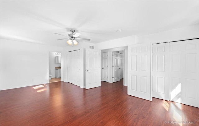 unfurnished bedroom with a ceiling fan, wood finished floors, ensuite bath, baseboards, and visible vents