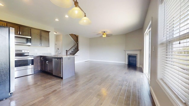 750 Sedgegrass Dr, Champaign, IL 61822 - kitchen with appliances with stainless steel finishes, a sink, a ceiling fan, a peninsula, and a glass covered fireplace