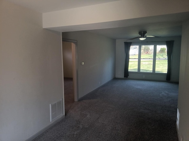 empty room featuring dark carpet, visible vents, and ceiling fan