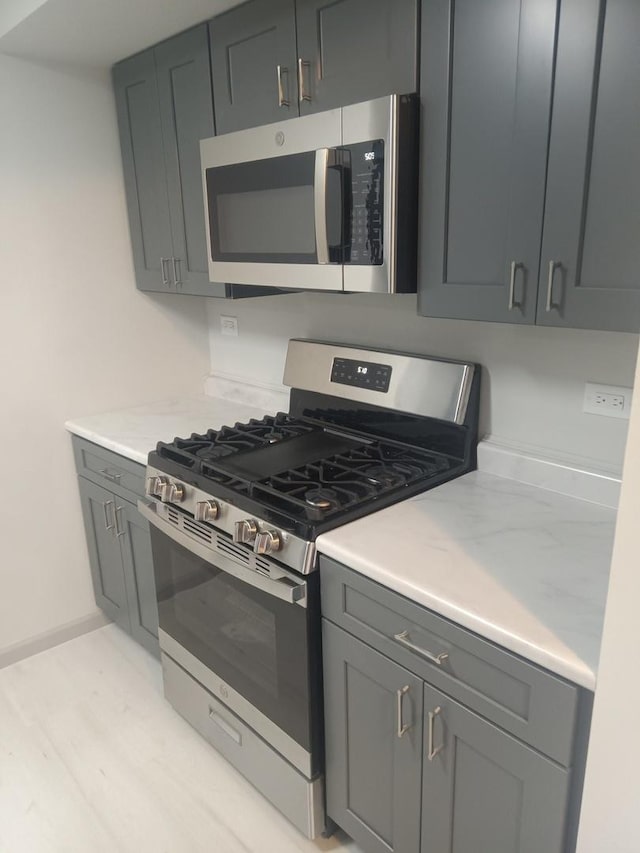 kitchen with gray cabinets, baseboards, and appliances with stainless steel finishes