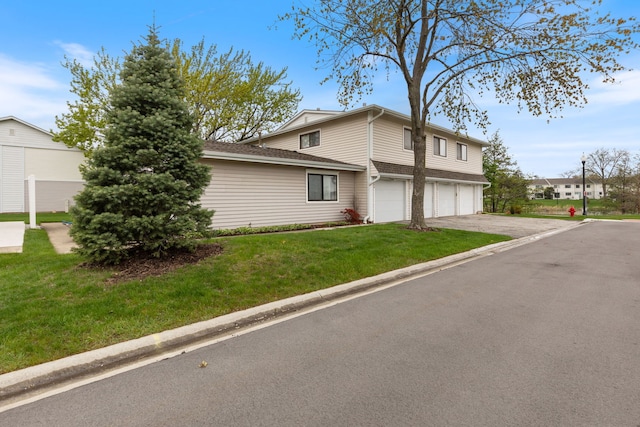 view of side of home featuring a lawn, driveway, and a garage