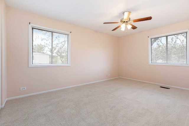 carpeted spare room with a ceiling fan, baseboards, and visible vents