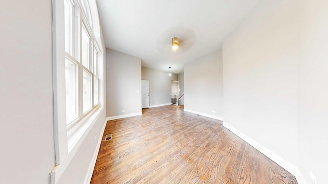 unfurnished room featuring visible vents, light wood-style flooring, and baseboards