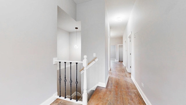 corridor with an upstairs landing, light wood-type flooring, and baseboards