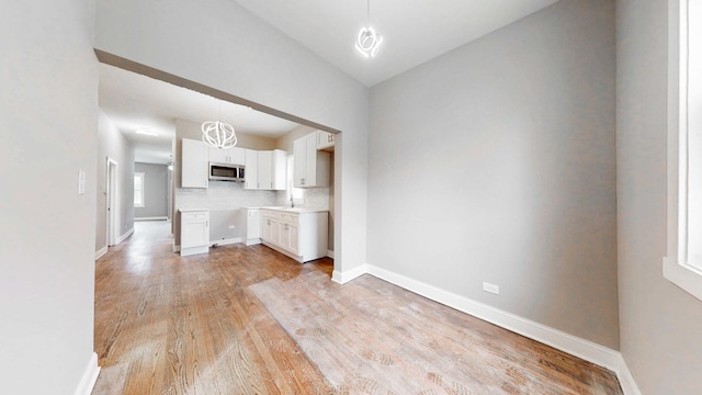 interior space featuring vaulted ceiling, light wood-style floors, baseboards, and a sink