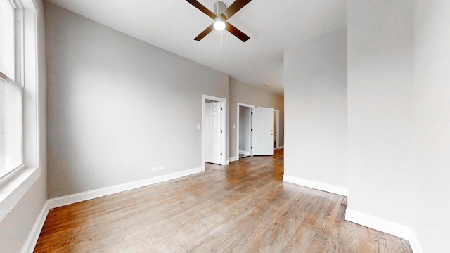 unfurnished room with wood finished floors, a ceiling fan, and baseboards