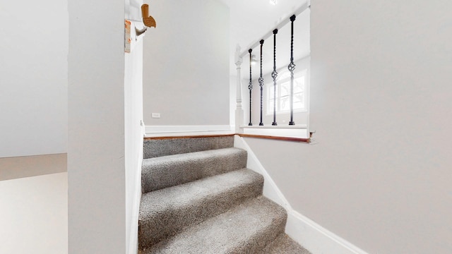 stairway with baseboards and carpet floors