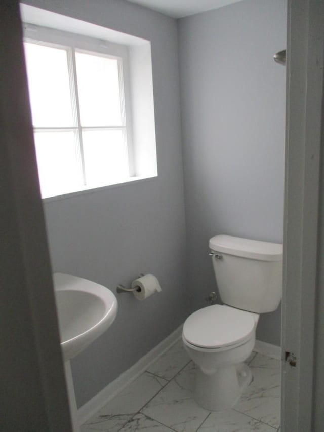 half bathroom featuring baseboards, marble finish floor, and toilet