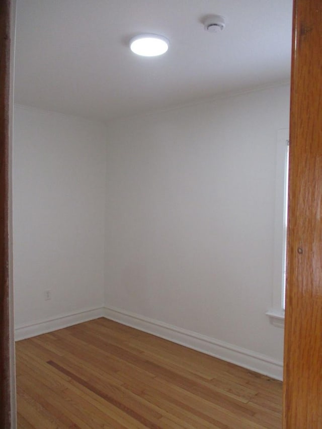 empty room featuring light wood-type flooring and baseboards