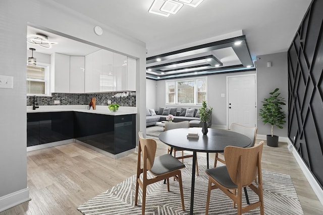 1158 W 111th St, Chicago, IL 60643 - dining area featuring light wood finished floors, a tray ceiling, and baseboards