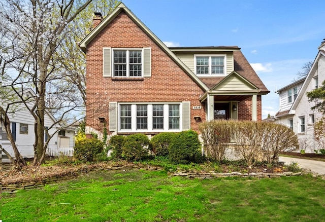 view of front facade featuring a chimney, a front lawn, and brick siding
