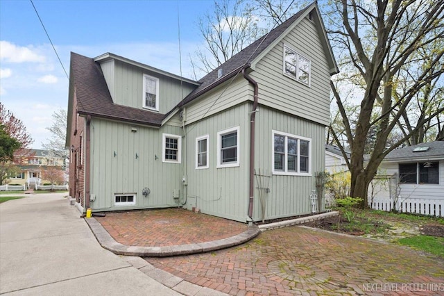 back of property featuring a shingled roof and a patio