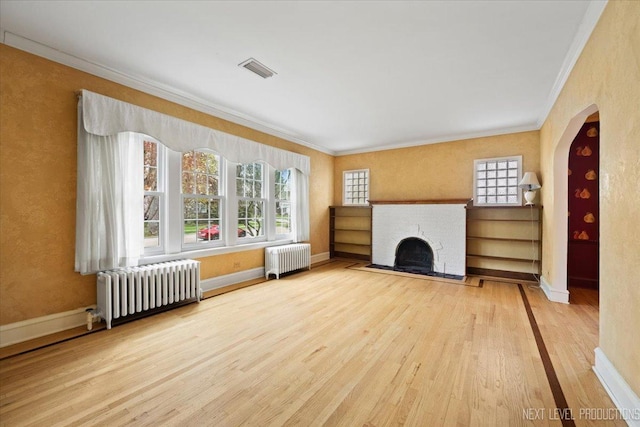 unfurnished living room featuring radiator heating unit, visible vents, crown molding, and wood finished floors
