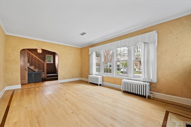 interior space with radiator, arched walkways, crown molding, and wood finished floors