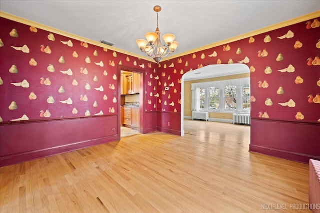 empty room featuring visible vents, a chandelier, ornamental molding, and radiator