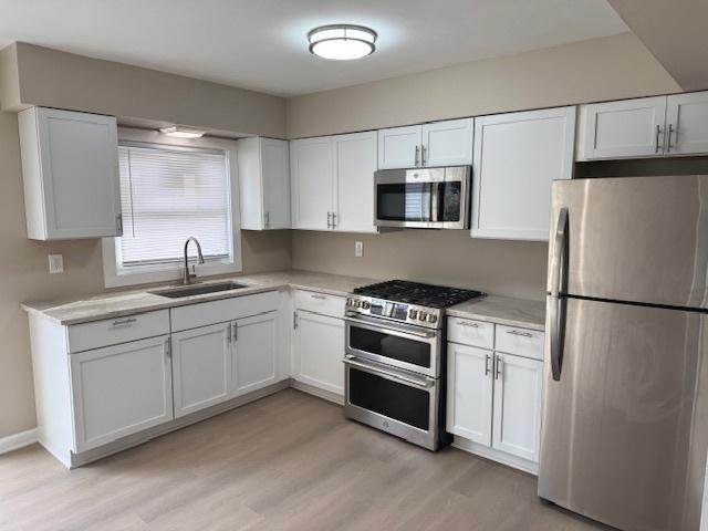 1507 7th St, Winthrop Harbor, IL 60096 - kitchen with appliances with stainless steel finishes, light countertops, white cabinets, and light wood-style floors