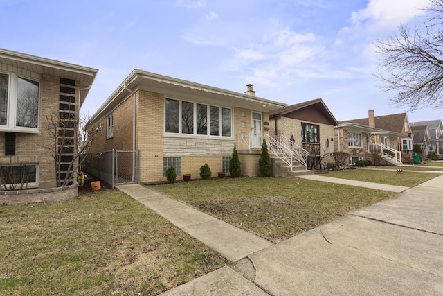 view of front facade with a front yard, a gate, fence, and brick siding