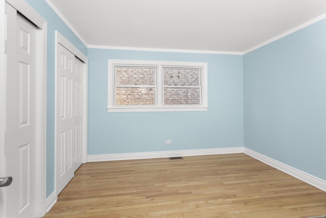 unfurnished bedroom featuring visible vents, baseboards, light wood-style floors, and ornamental molding