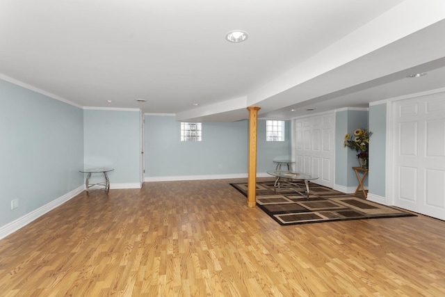 below grade area featuring baseboards, crown molding, and light wood-style floors