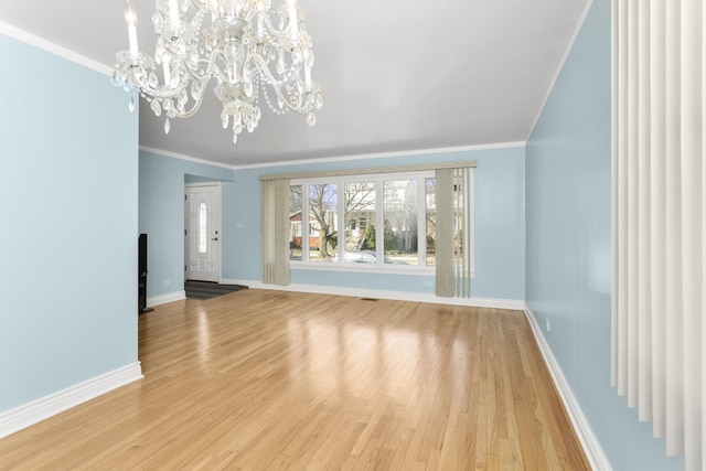 unfurnished living room featuring baseboards, light wood-style floors, an inviting chandelier, and ornamental molding
