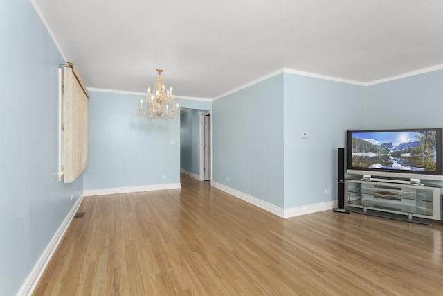 unfurnished living room featuring ornamental molding, baseboards, an inviting chandelier, and wood finished floors