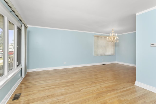 spare room with visible vents, crown molding, light wood finished floors, baseboards, and a chandelier