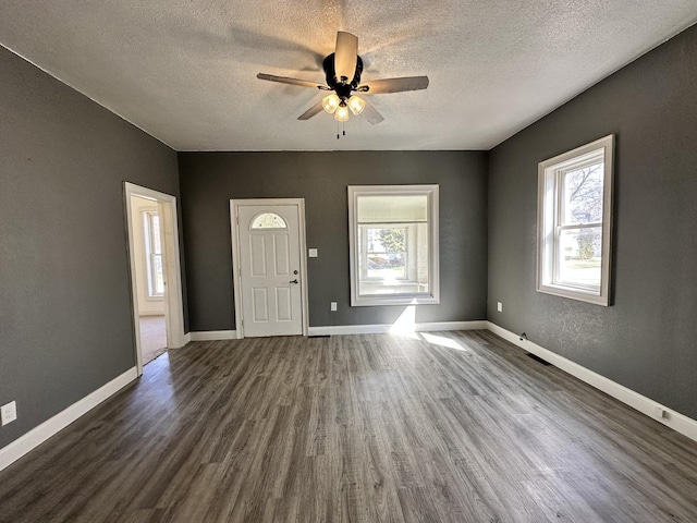 foyer entrance featuring dark wood finished floors, a ceiling fan, and baseboards