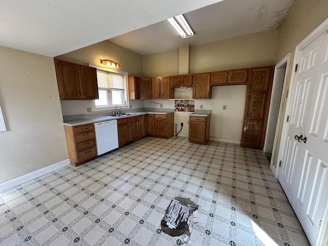 kitchen featuring brown cabinetry, light floors, white dishwasher, and baseboards