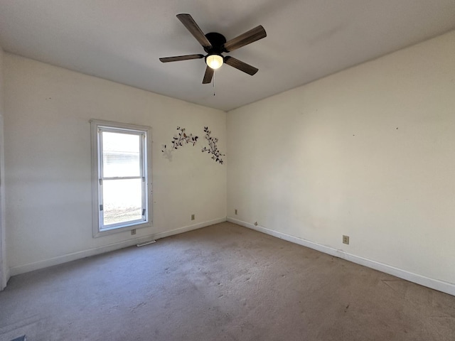 carpeted empty room featuring baseboards and a ceiling fan