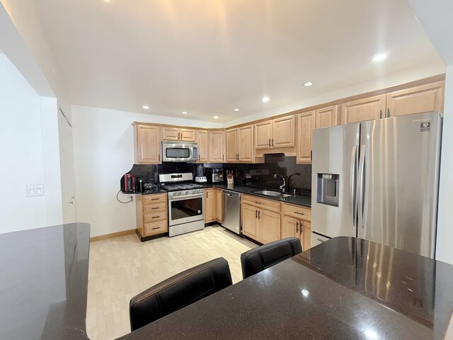 kitchen with stainless steel appliances, light brown cabinets, and a sink