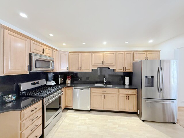 kitchen with decorative backsplash, a sink, dark countertops, light brown cabinets, and stainless steel appliances