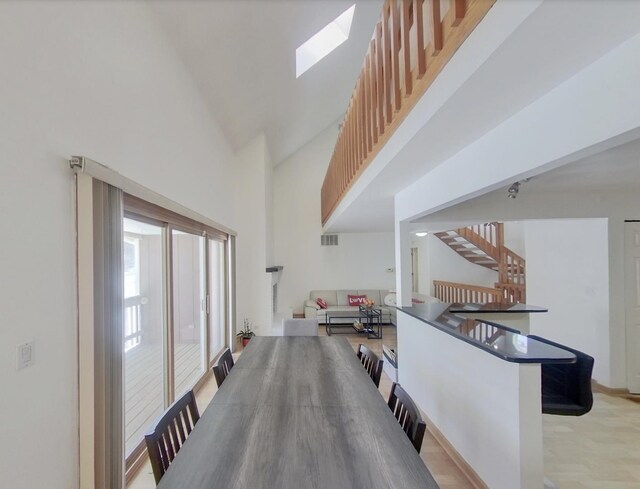 interior space featuring a high ceiling, visible vents, a skylight, and stairs