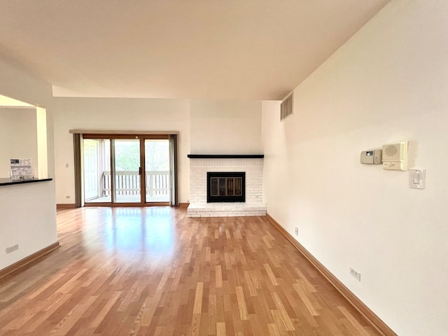unfurnished living room featuring baseboards, light wood-type flooring, visible vents, and a fireplace