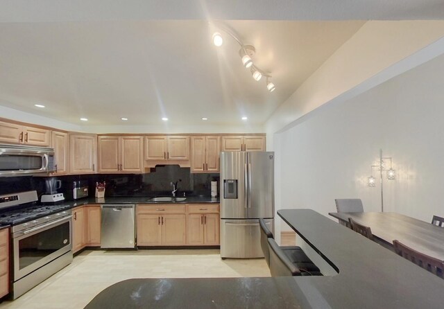 kitchen featuring a sink, stainless steel appliances, light brown cabinets, tasteful backsplash, and dark countertops