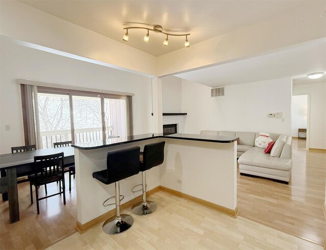 kitchen with visible vents, light wood-style floors, and a glass covered fireplace