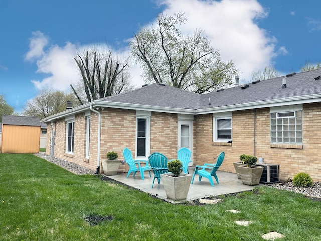 1299 Riverlane Dr, Bradley, IL 60915 - rear view of house featuring brick siding, a storage unit, a lawn, an outbuilding, and a patio area