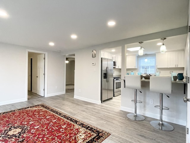 1299 Riverlane Dr, Bradley, IL 60915 - kitchen with a breakfast bar area, appliances with stainless steel finishes, a peninsula, light wood-style flooring, and white cabinets